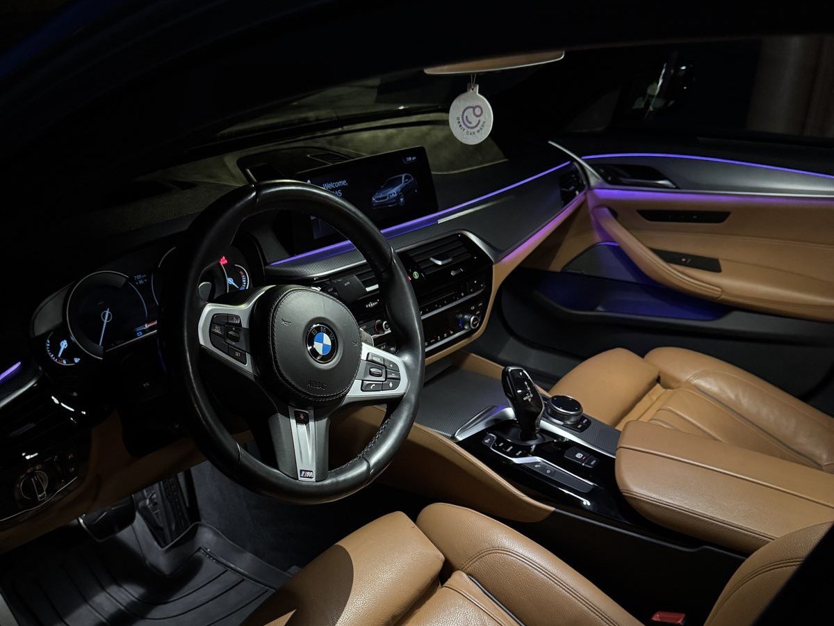 BMW M5 interior with tan leather seats under ambient lighting